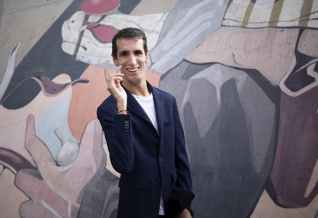 Hombre posando a una fotografía y de fondo un mural