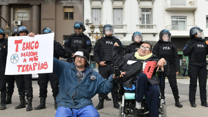 Foto de persona en silla de ruedas y su cuidador manifestándose en Argentina