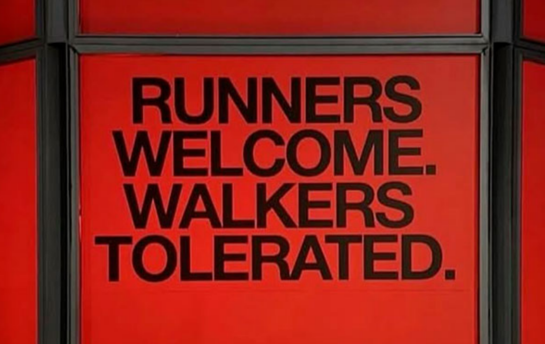 Anuncio de fondo rojo con letras negras que dice "Runners welcome, walkers tolerated"