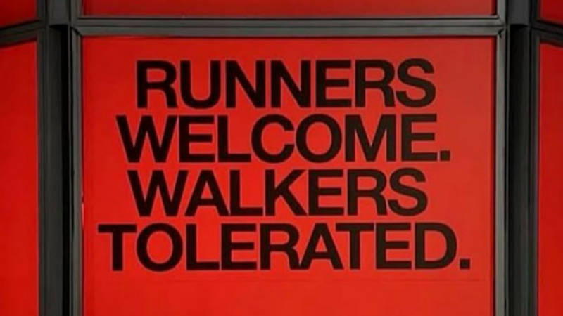 Anuncio de fondo rojo con letras negras que dice "Runners welcome, walkers tolerated"