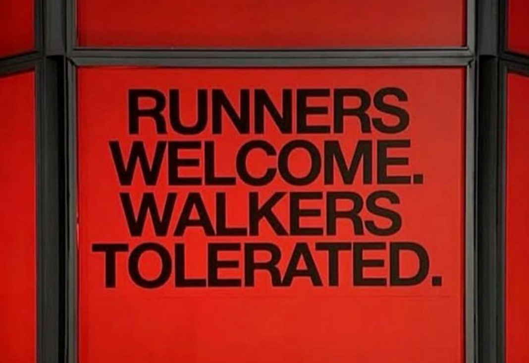 Anuncio de fondo rojo con letras negras que dice "Runners welcome, walkers tolerated"