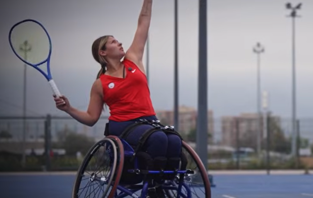 Mujer en silla de ruedas lanzando una pelota de tenis y con una raqueta