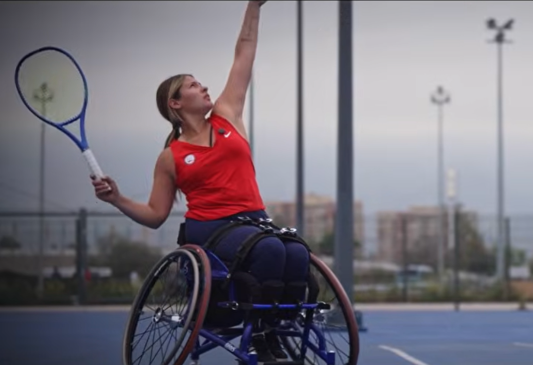 Mujer en silla de ruedas lanzando una pelota de tenis y con una raqueta