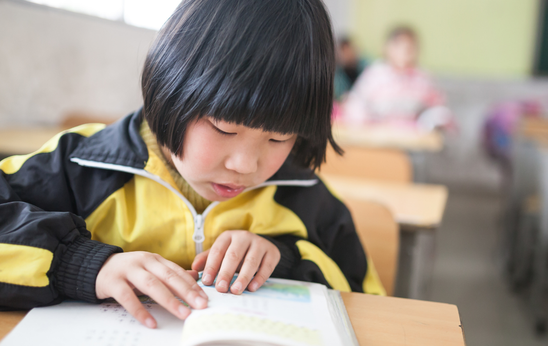 Niña china leyendo sentada en una sala de clases