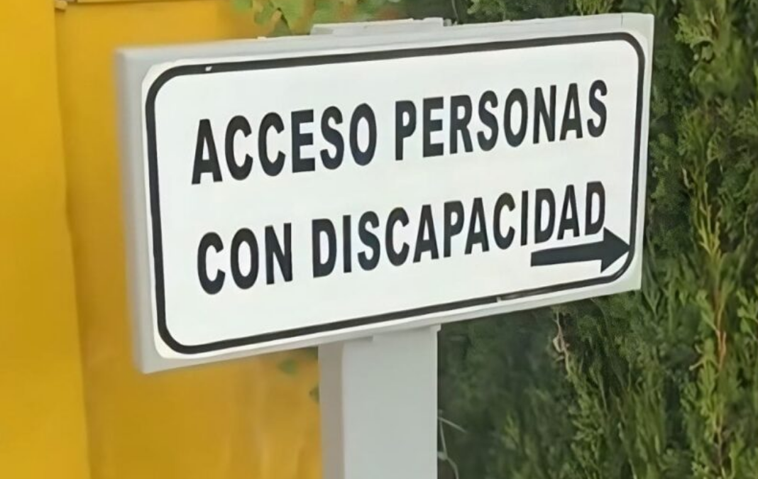 Fotografía de letrero blanco con letras negras que dice "acceso personas con discapacidad"