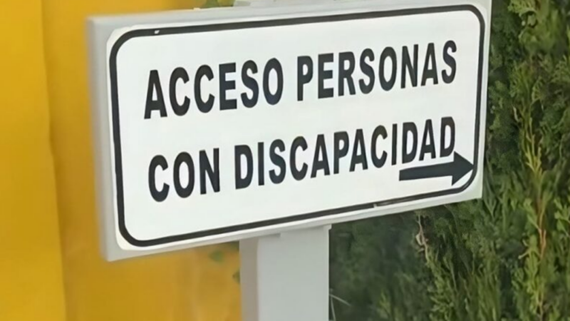 Fotografía de letrero blanco con letras negras que dice "acceso personas con discapacidad"