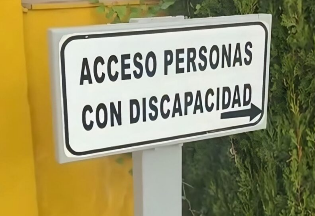 Fotografía de letrero blanco con letras negras que dice "acceso personas con discapacidad"