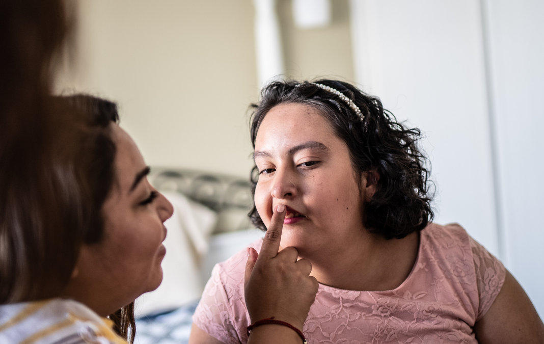 Fotografía de joven con discapacidad intelectual y otra mujer le limpia los labios