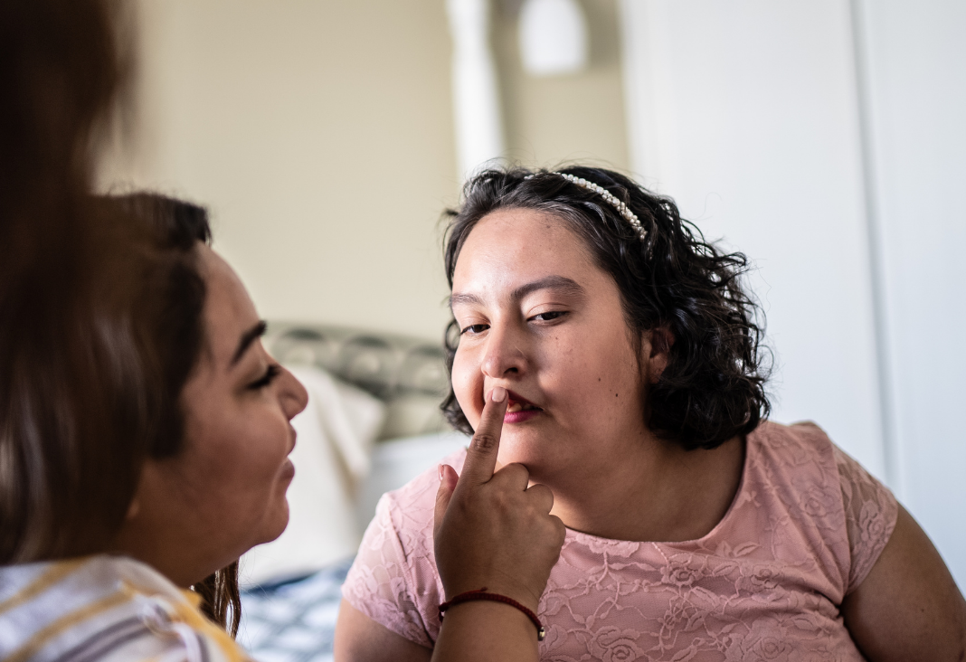 Fotografía de joven con discapacidad intelectual y otra mujer le limpia los labios