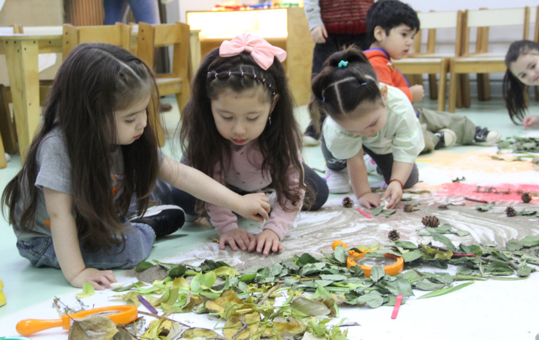 Foto de tres niñas creando una pintura con hojas