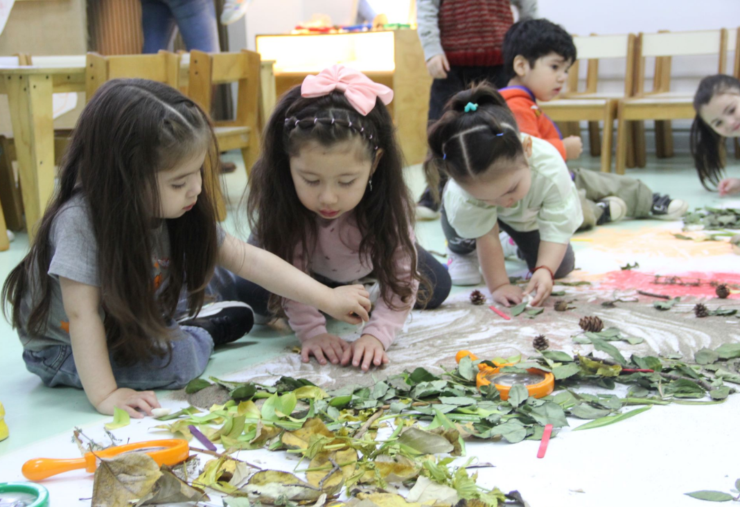 Foto de tres niñas creando una pintura con hojas