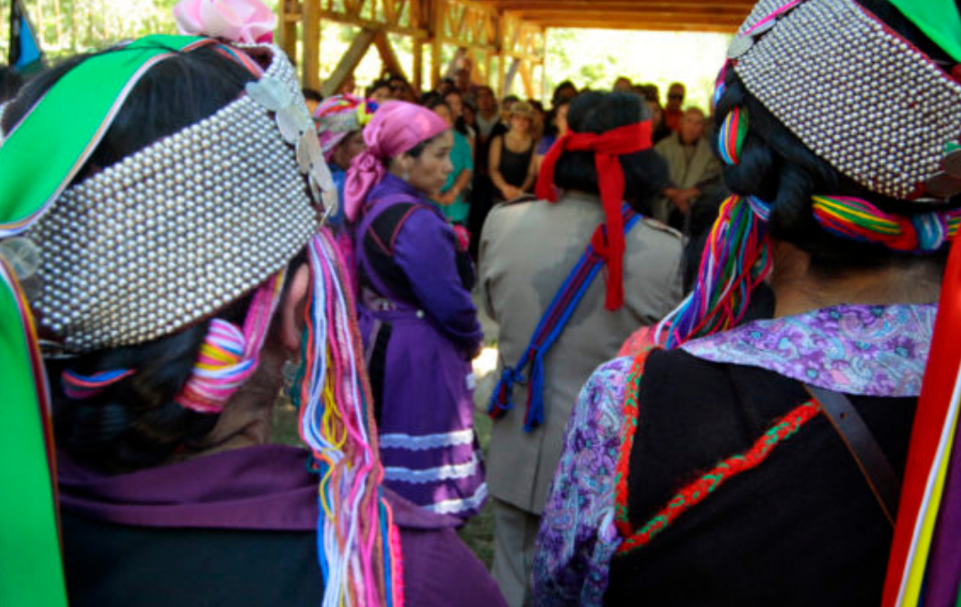 Jóvenes mapuche de espalda con su vestimenta tradicional