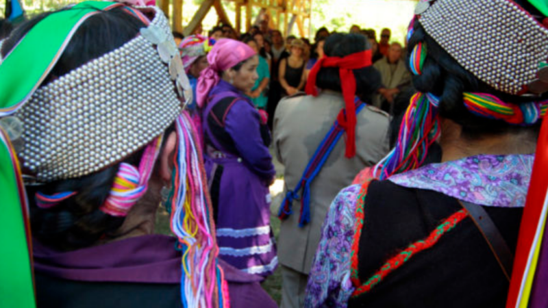 Jóvenes mapuche de espalda con su vestimenta tradicional