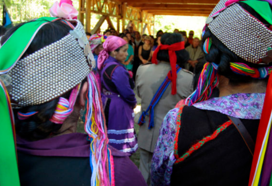 Jóvenes mapuche de espalda con su vestimenta tradicional