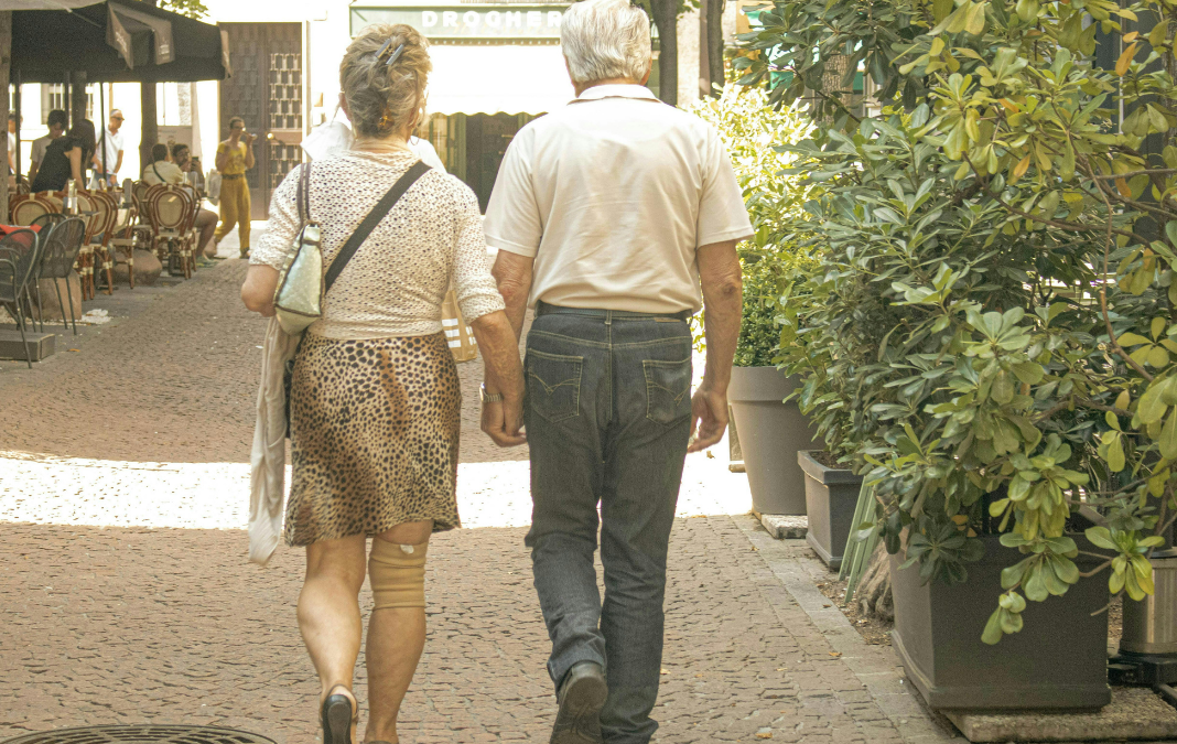 Fotografía de pareja de mujer y hombre mayor de espaldas caminando por la calle