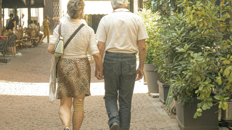 Fotografía de pareja de mujer y hombre mayor de espaldas caminando por la calle
