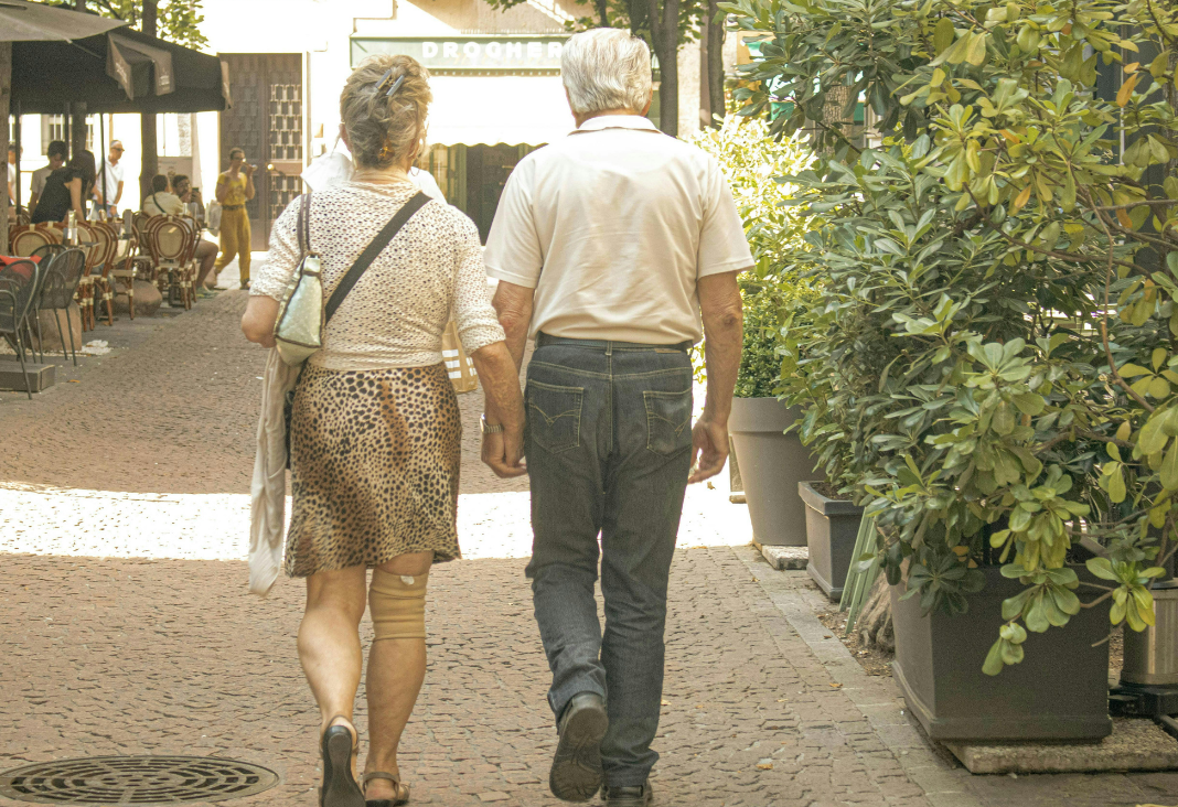 Fotografía de pareja de mujer y hombre mayor de espaldas caminando por la calle