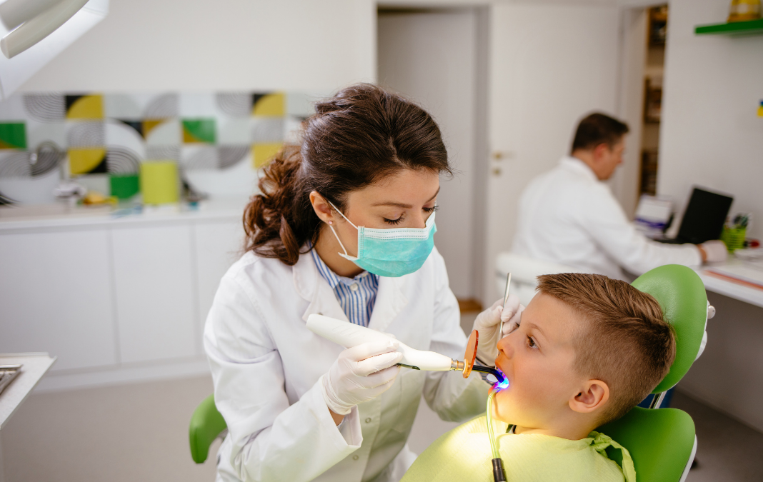 Niño sentado mientras una dentista lo atiende