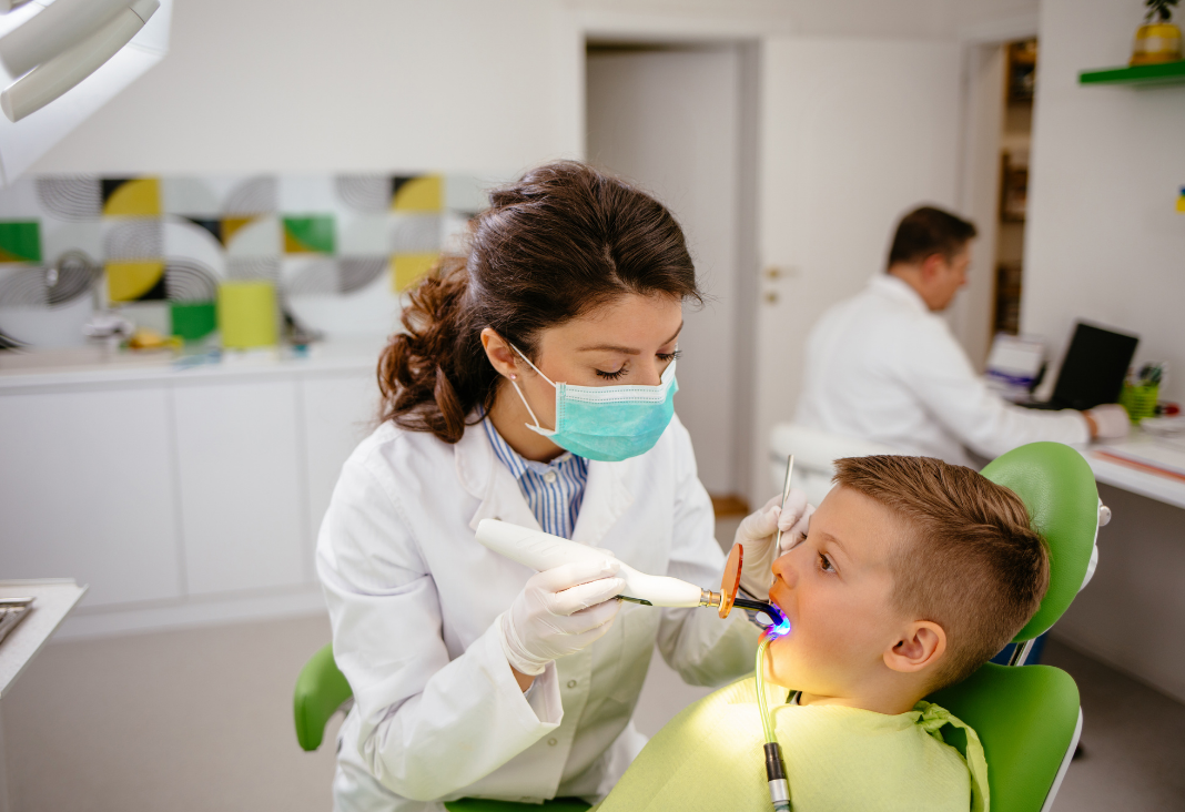 Niño sentado mientras una dentista lo atiende