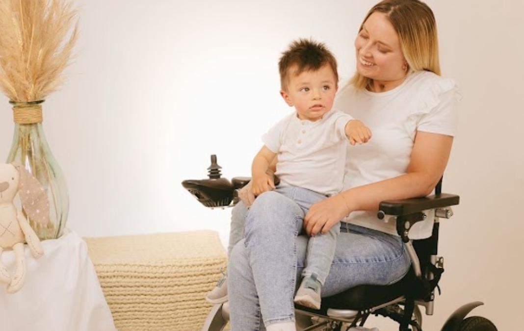 Foto de mujer en silla de ruedas y con un niño pequeño en brazos