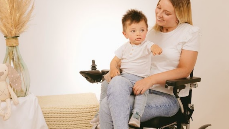Foto de mujer en silla de ruedas y con un niño pequeño en brazos