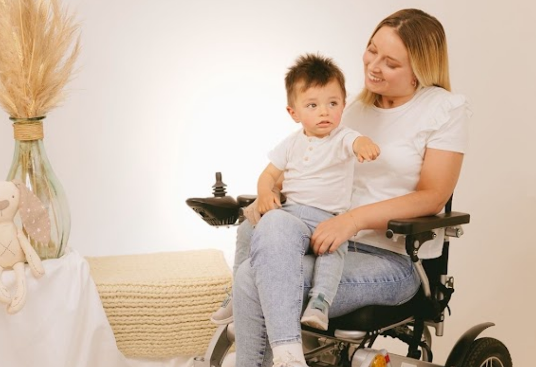 Foto de mujer en silla de ruedas y con un niño pequeño en brazos