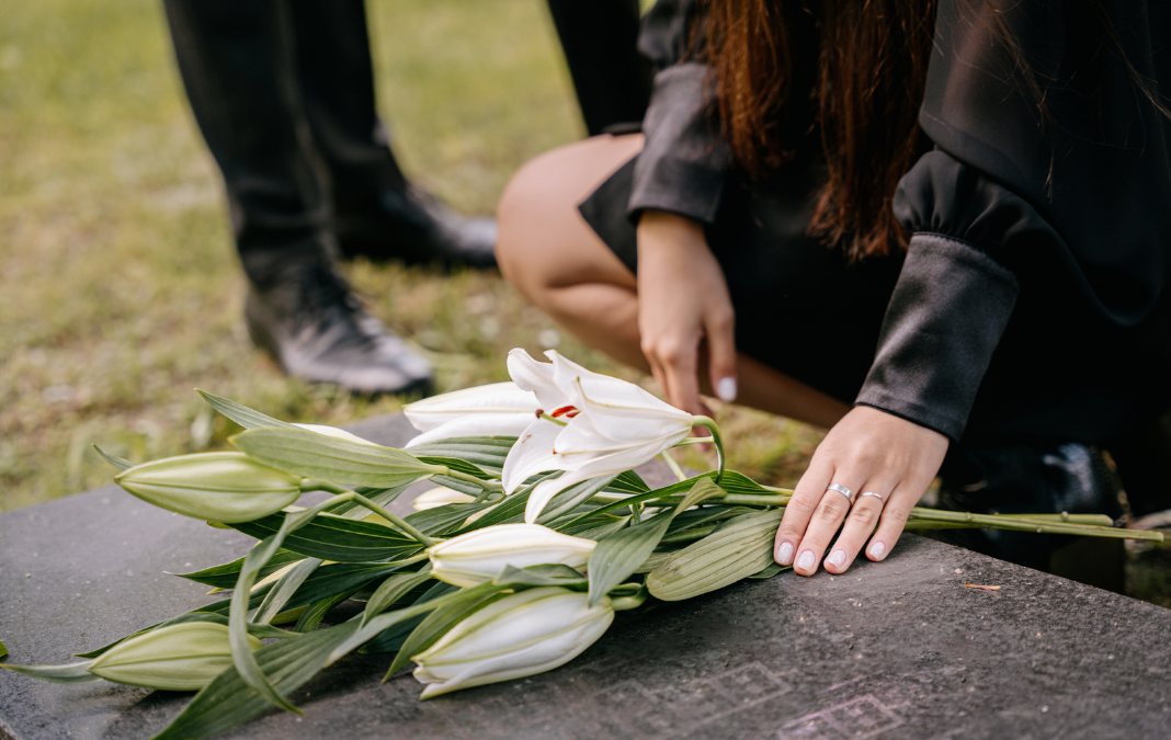 Mujer dejando flores sobre una tumba