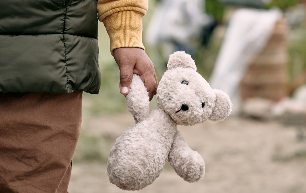 Mano de un niño sujetando un oso de peluche
