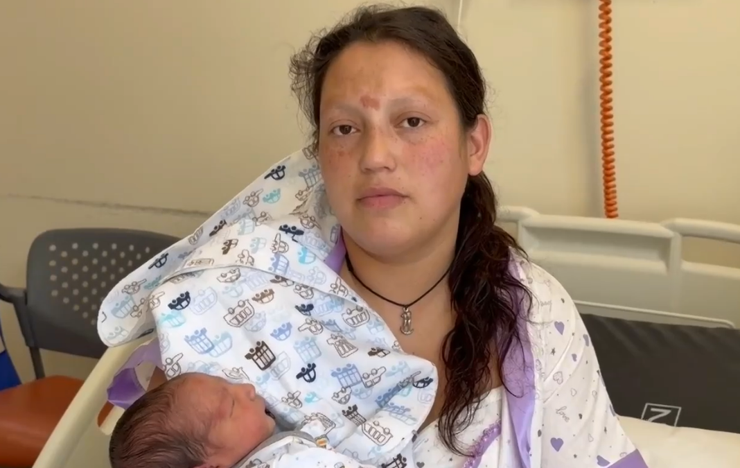 Mujer mirando de frente con su bebé en brazos