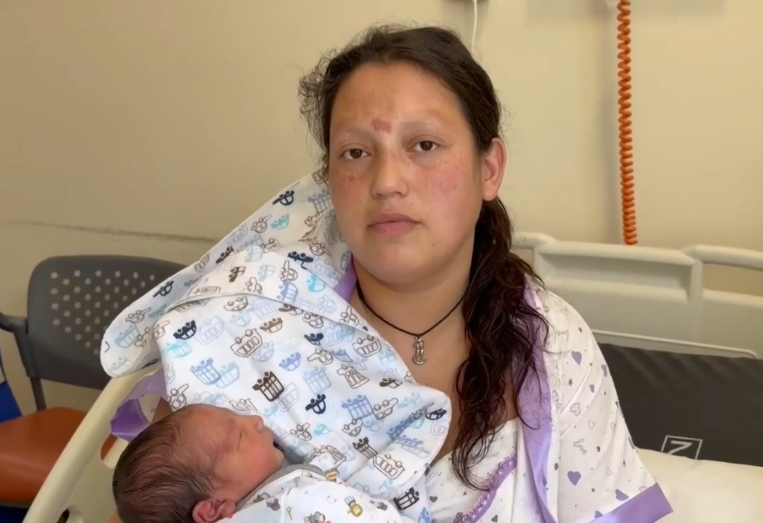 Mujer mirando de frente con su bebé en brazos