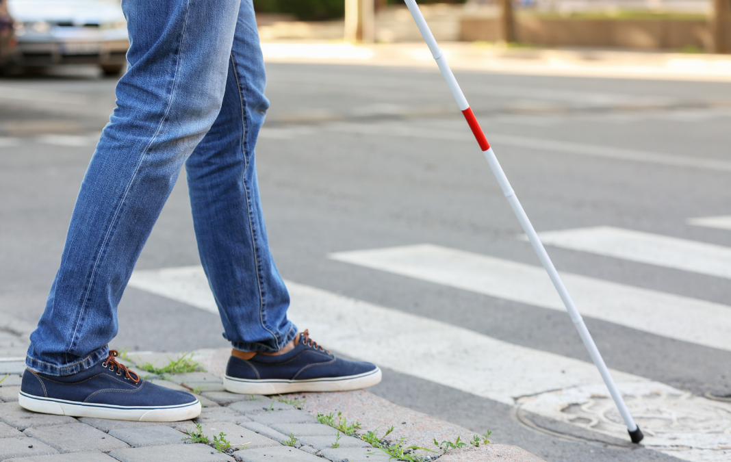 Persona ciega con bastón cruzando un paso peatonal