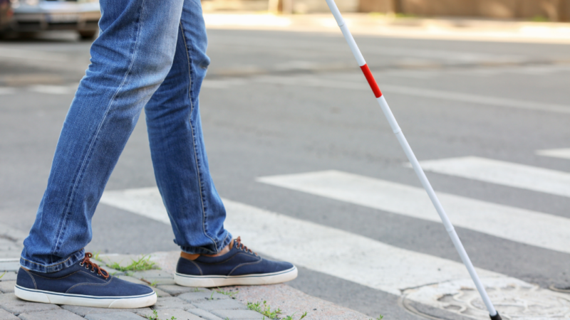 Persona ciega con bastón cruzando un paso peatonal