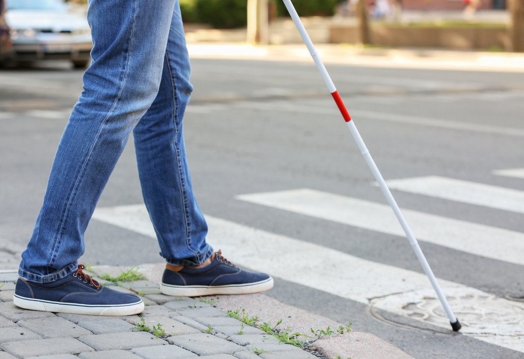 Persona ciega con bastón cruzando un paso peatonal