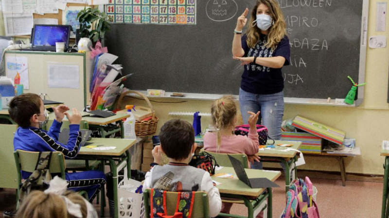 Mujer enseñando lengua de señas a niñas y niños en una sala de clases