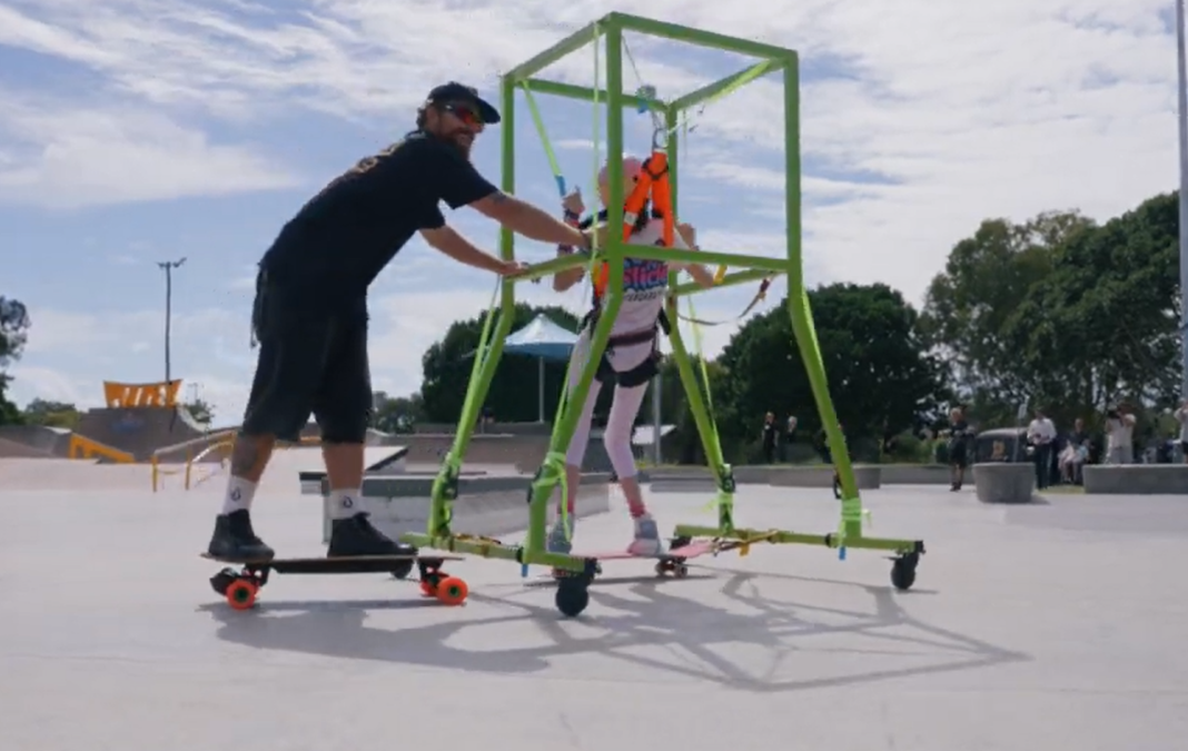 Hombre en skate empuja soporte de skate para personas en silla de ruedas