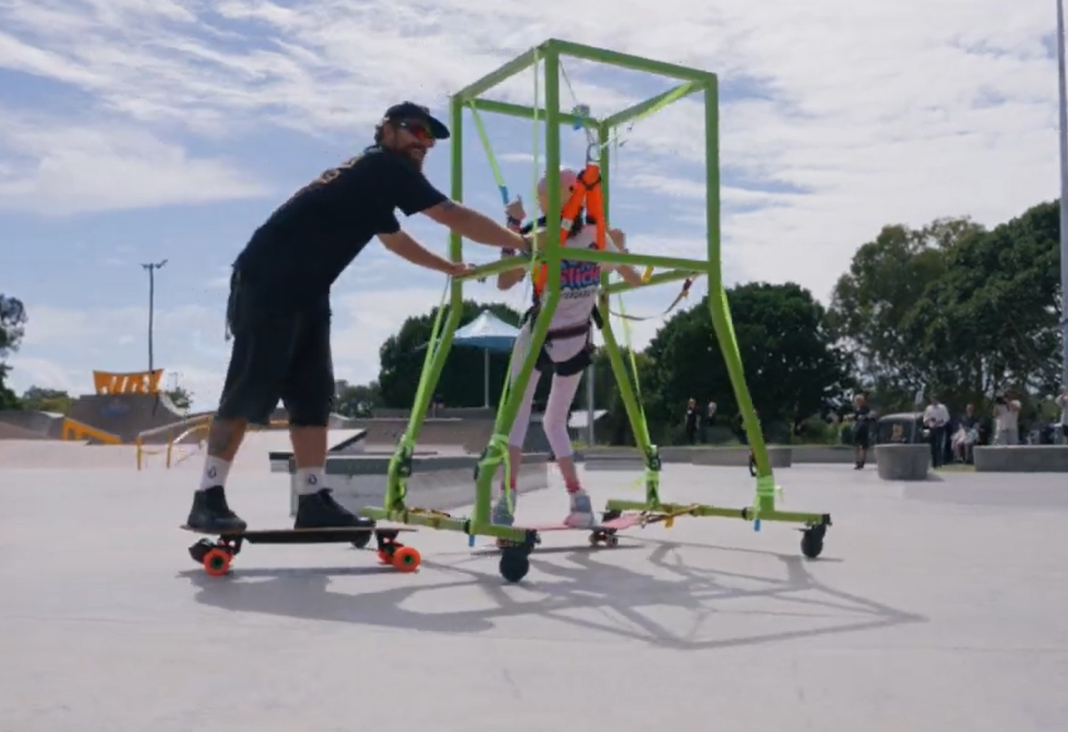 Hombre en skate empuja soporte de skate para personas en silla de ruedas