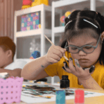 niña con síndrome de Down pintando y atrás otro niño