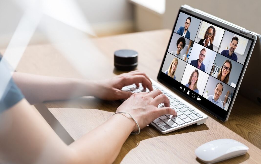 manos de mujer escribiendo teclado frente a una videollamada