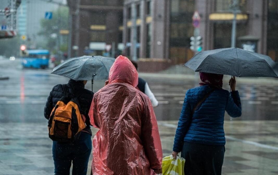 Personas esperando cruzar la calle bajo la lluvia