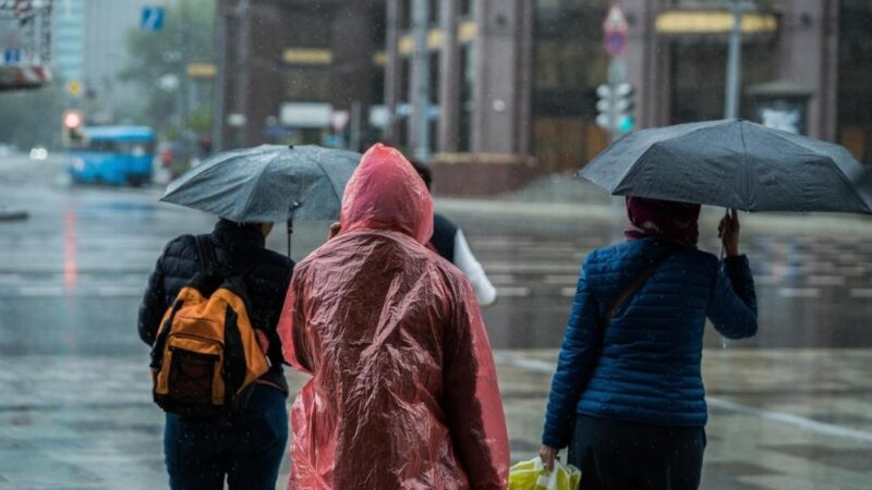 Personas esperando cruzar la calle bajo la lluvia