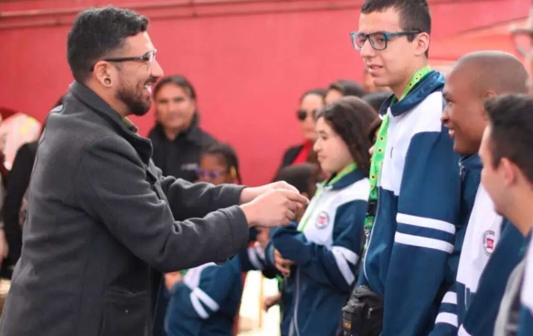 Hombre entregando a un joven un lanyard verde con girasoles