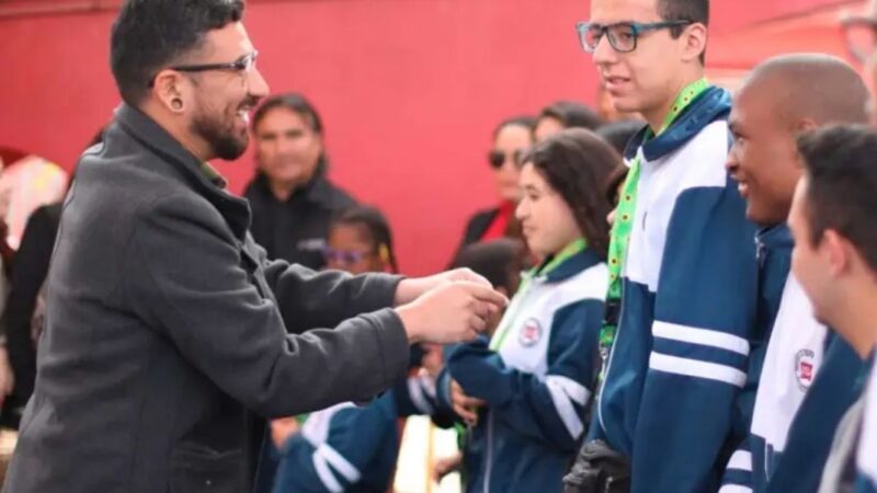 Hombre entregando a un joven un lanyard verde con girasoles