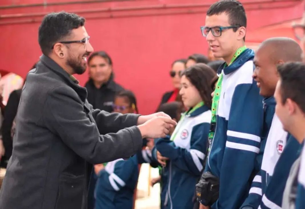 Hombre entregando a un joven un lanyard verde con girasoles