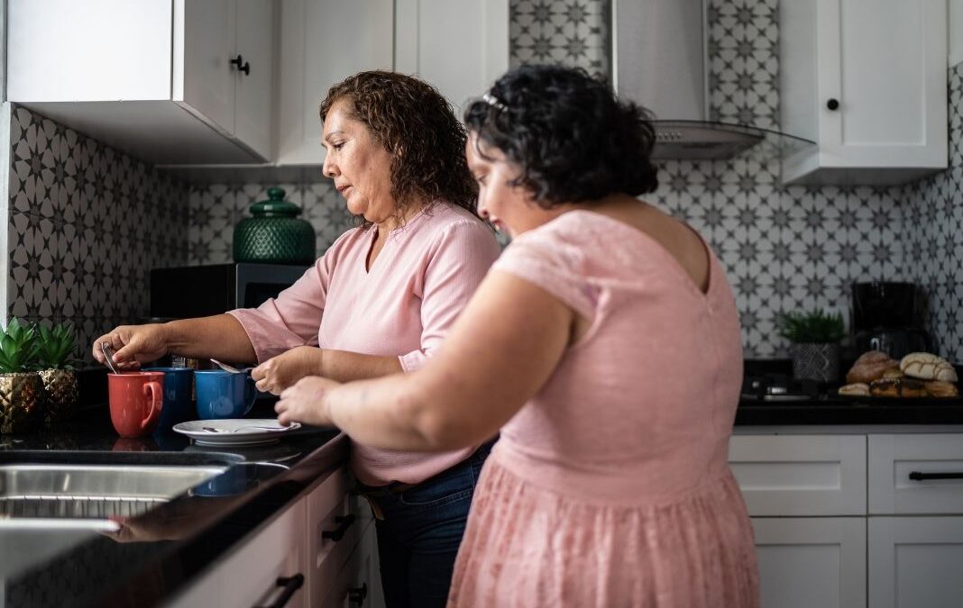 Una mujer preparando unas tazas de té junto a su hija con discapacidad