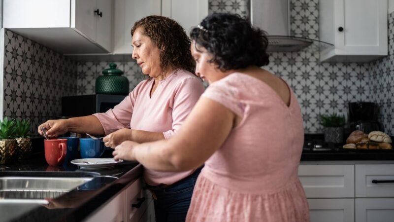 Una mujer preparando unas tazas de té junto a su hija con discapacidad