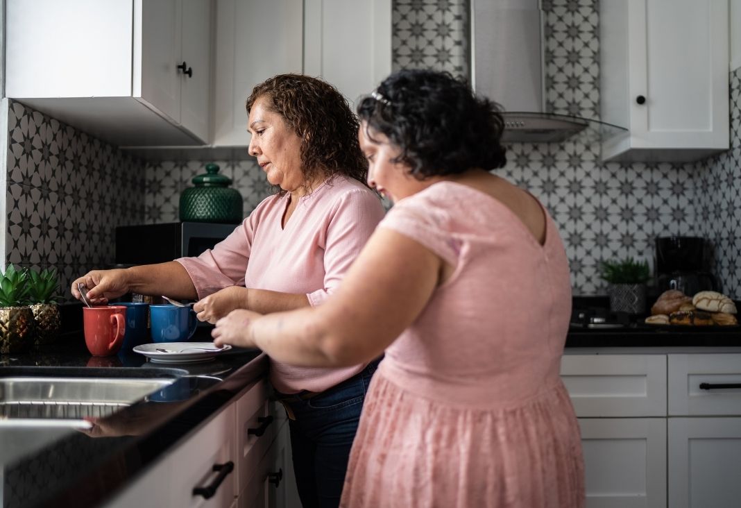 Una mujer preparando unas tazas de té junto a su hija con discapacidad