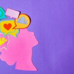 Silueta hecha con papel de una mujer con distintos emojis en su cerebro