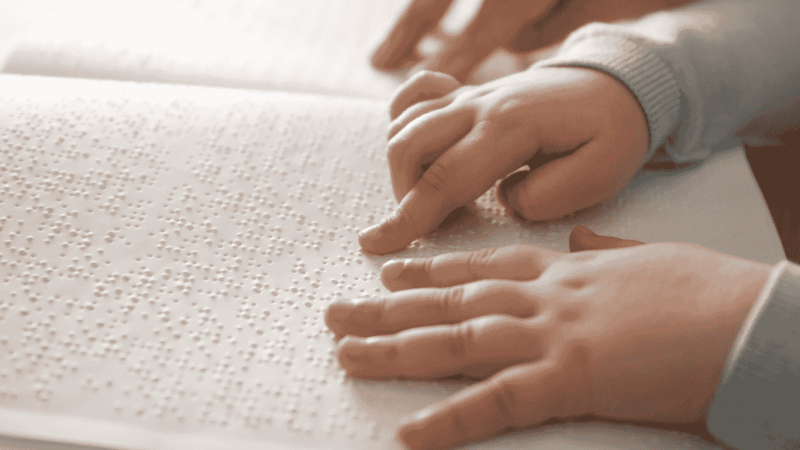 manos de niño leyendo un libro en braille