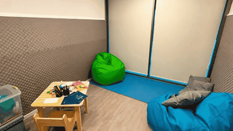Sala de calma con unos puff, una mesa y diversos objetos para dibujar