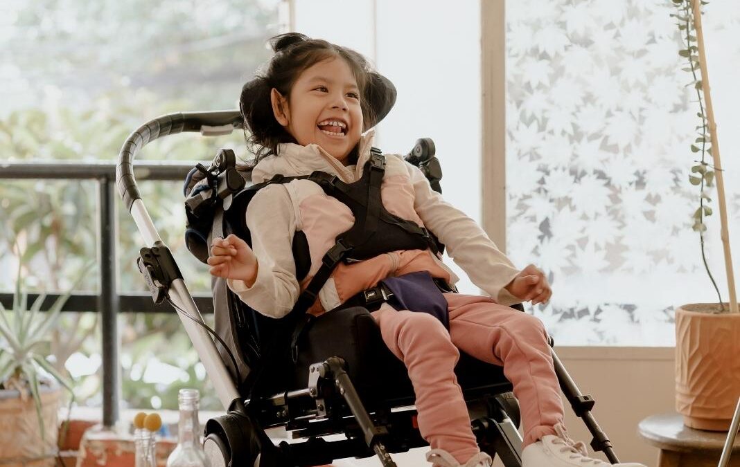 Niña con discapacidad sonriendo y sentada en un coche